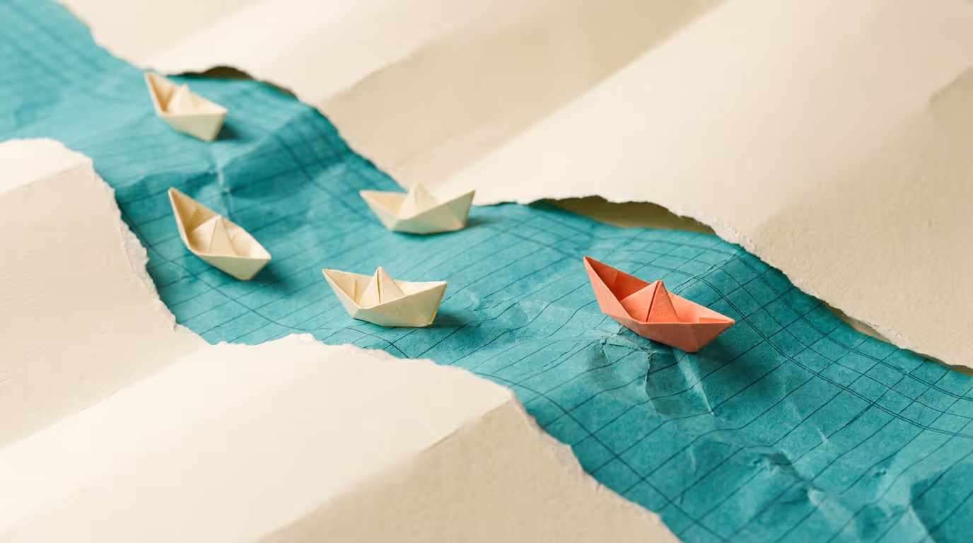 Paper craft scene of five origami boats racing along a folded teal paper river, one pulling ahead